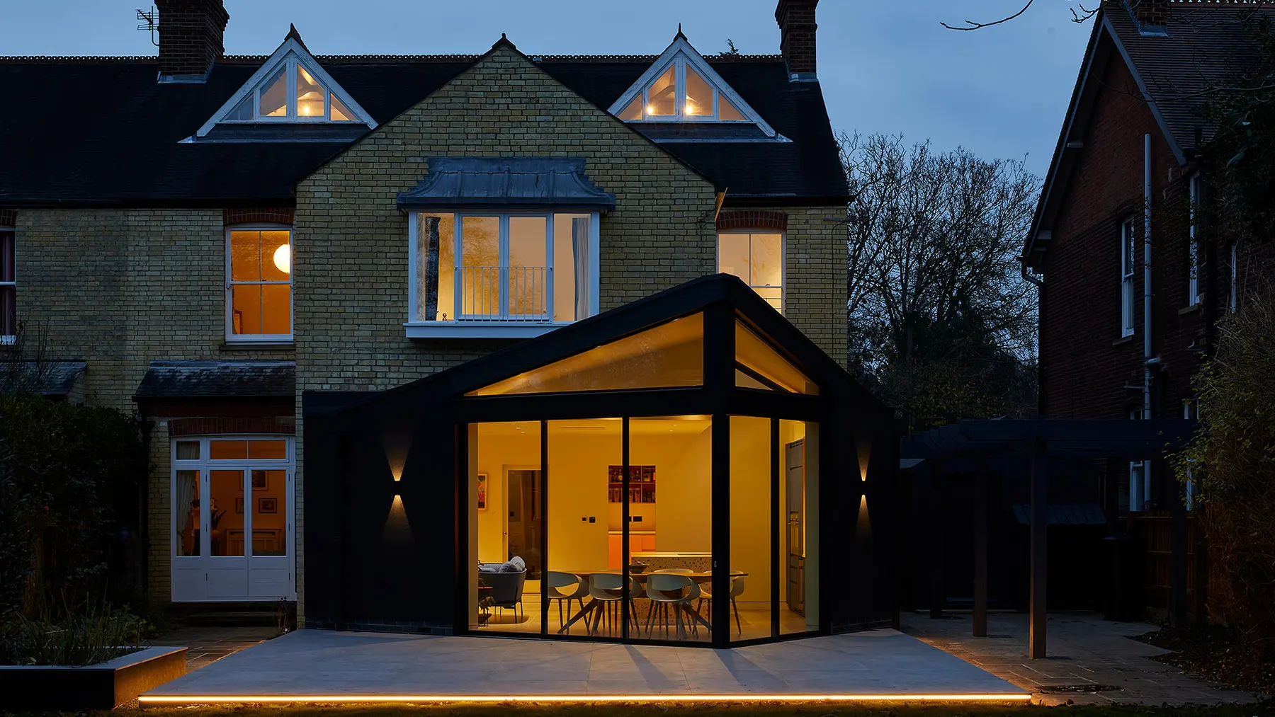 Full rear elevation of the Victorian house and contemporary glazed extension at dusk